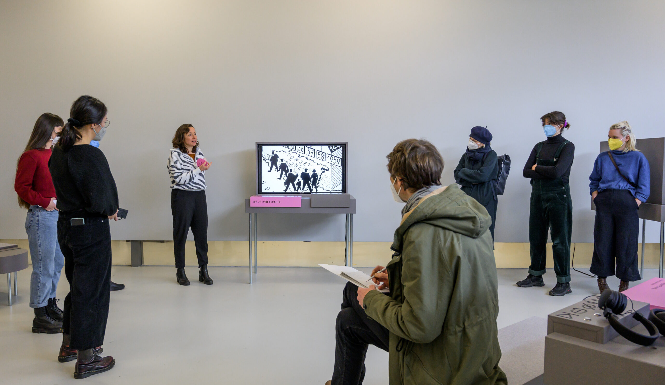 Personen, die während einer Vermittlungsrunde ein Video in der Ausstellung ansehen